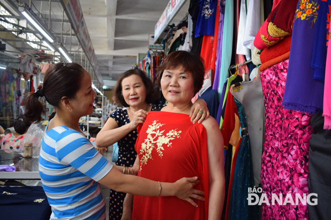 Chị Trần Thúy Kiều (bên trái), chủ cửa hàng may đo Kiều ở chợ Hàn đang tư vấn và thực hiện việc cắt may áo dài cho khách du lịch. Ảnh: M.Đ