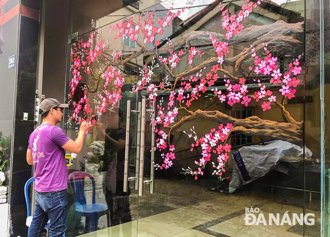  A young artist being keen on drawing a mural of peach blossoms on the glass surface