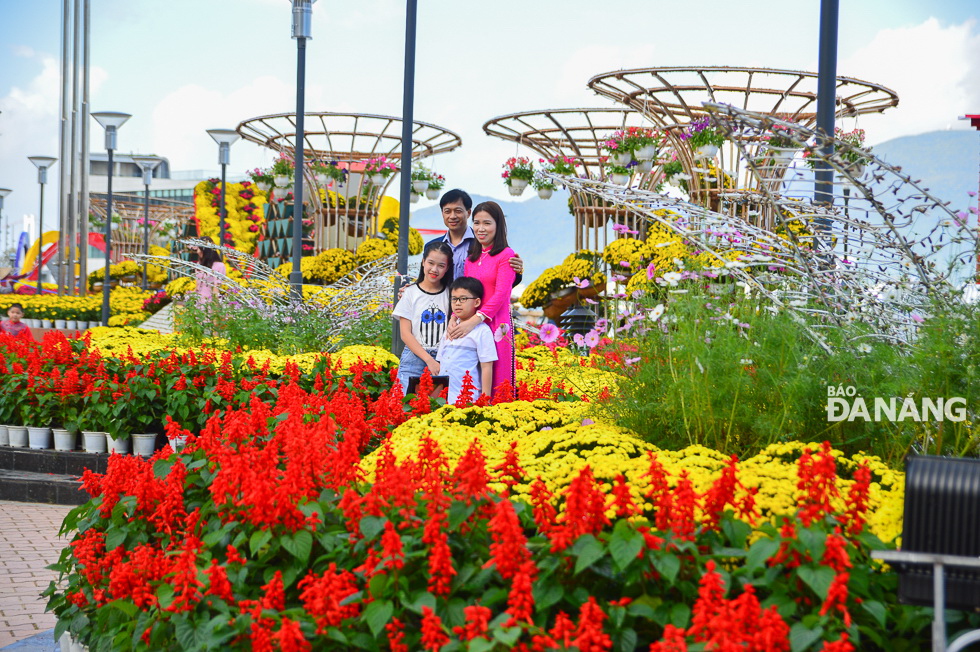 A family posing for a souvenir photo with colourful flowers.
