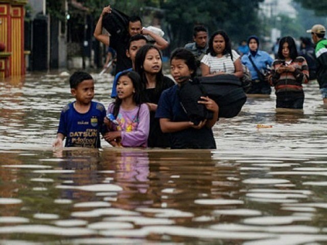 Residents walking along a flooded road as they evacuate Dayeuhkolot village in Bandung. (Photo: AFP)