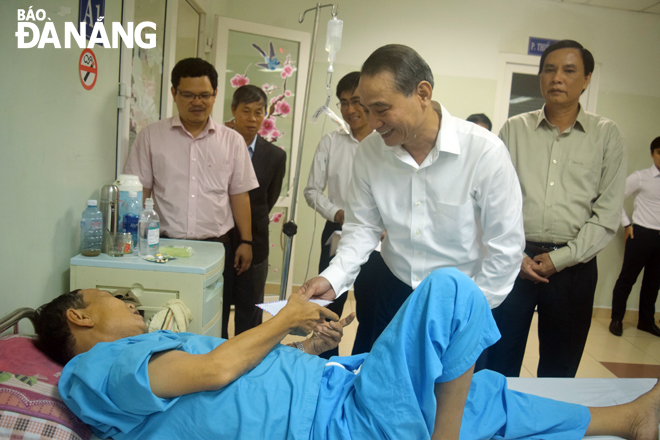 Secretary Nghia presenting a gift to a patient at the Cancer Hospital