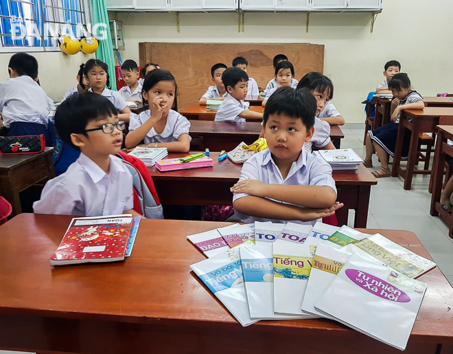 Học sinh trường Tiểu học Lê Lai bên những cuốn sách, cuốn vở bọc giấy do phụ huynh tự thiết kế bìa.