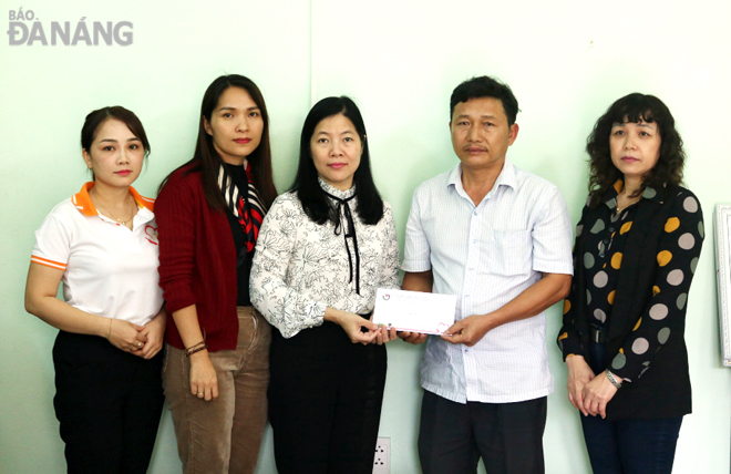 Director of the municipal Department of Education and Training Le Thi Bich Thuan (centre) and Vice Chairwoman of the Da Nang Journalists’ Association Phan Hoang Phuong (right) presenting a gift to the family of 9th grader Le Dang Hoang Huy