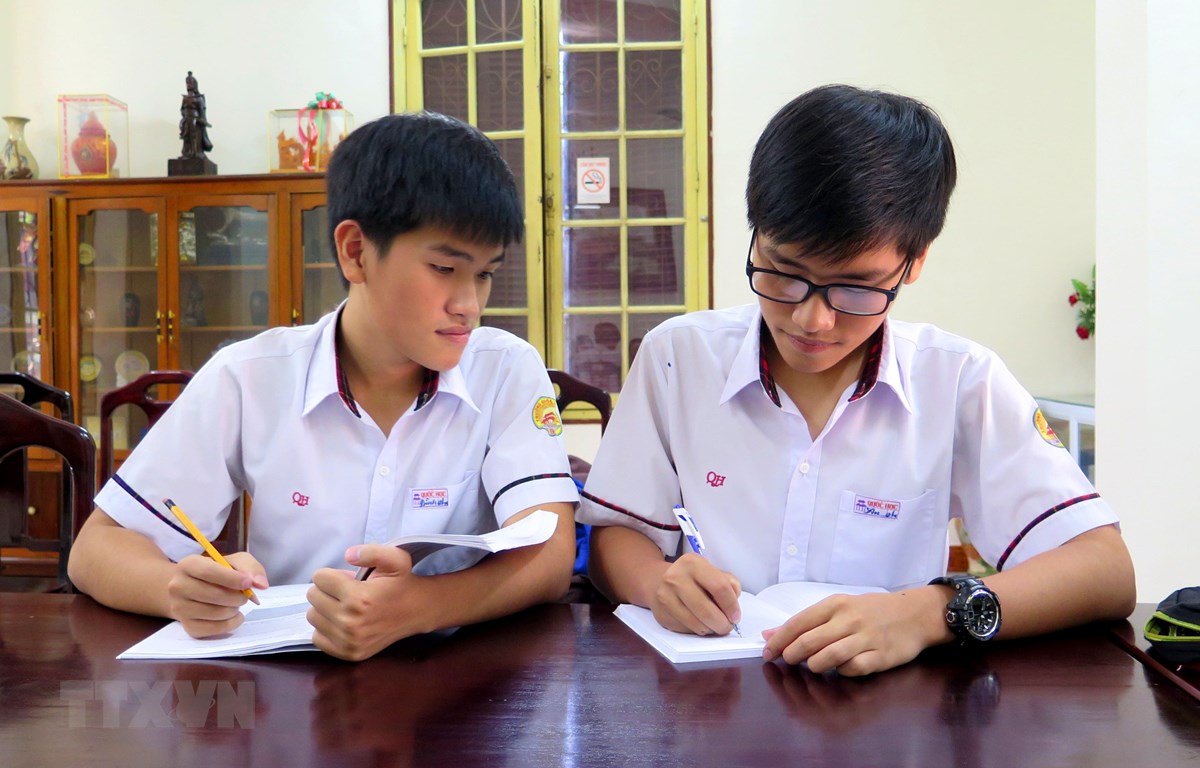Hai anh em Tống Phước Thanh Bình và Tống Phước Thanh An (người đeo kính) trao đổi bài trước giờ lên lớp. (Ảnh: Tường Vi/TTXVN)