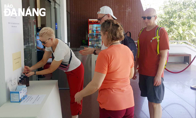 Du khách vệ sinh tay bằng nước diệt khuẩn trước khi vào tham quan Bảo tàng  Đà Nẵng. Ảnh: NGỌC HÀ