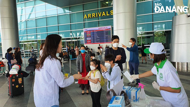 Sau khi xuống máy bay du khách được phát, tặng khẩu trang miễn phí. Trong ảnh: Du khách quốc tế đến Đà Nẵng nhận khẩu trang miễn phí và sử dụng nước sát khuẩn để vệ sinh tay ngay tại Cảng hàng không quốc tế Đà Nẵng. Ảnh; NHẬT HẠ.