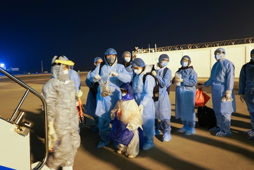30 công dân Việt Nam từ tâm dịch Vũ Hán xếp hàng lên máy bay với đồ bảo hộ chuẩn bị về nước. (Ảnh: Vietnam Airlines)
