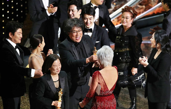 Đạo diễn Bong Joon-ho (giữa) vui mừng đón nhận sự chúc mừng của các đồng nghiệp khi “Parasite” thắng giải. Ảnh: Nytimes
