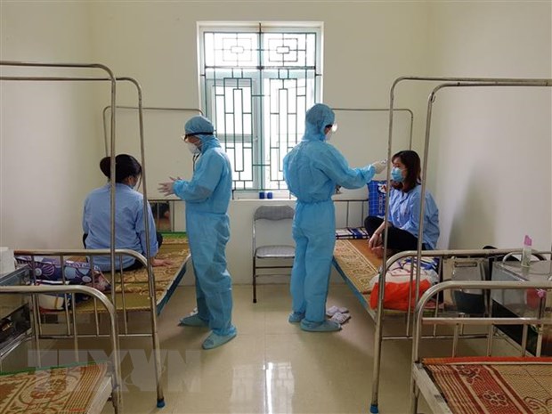 Các bác sỹ Trung tâm Y tế huyện Ân Thi đo thân nhiệt cho các em du học sinh. (Ảnh: Đinh Tuấn/TTXVN)