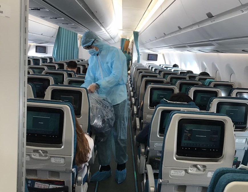 Các tiếp viên mặc trang phục bảo hộ phục vụ hành khách trong suốt 12-13 giờ bay. (Ảnh: VNA cung cấp)