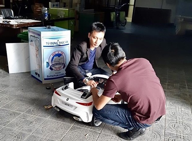 Thạc sỹ Huỳnh Phúc Minh (áo đen) chế tạo robot Tâm An. (Ảnh: Mai Trang/TTXVN)