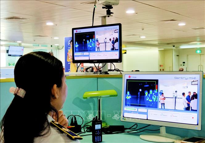 Nhân viên Trung tâm Kiểm dịch y tế quốc tế giám sát thân nhiệt của hành khách nhập cảnh tại sân bay Tân Sơn Nhất TP Hồ Chí Minh. Ảnh: TTXVN phát
