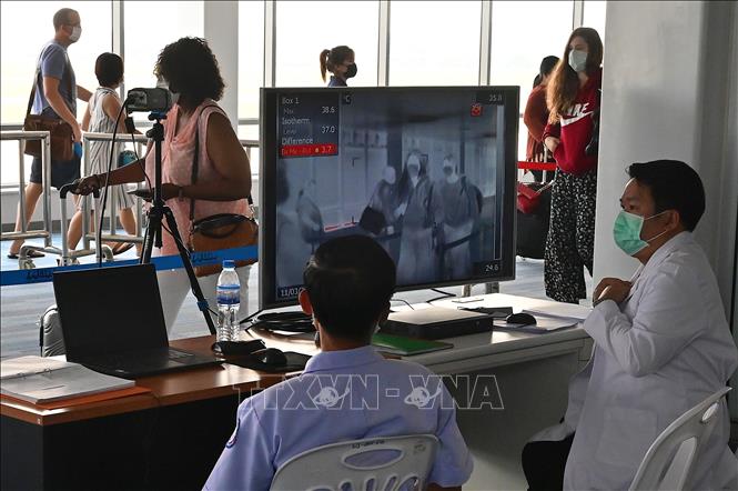 Nhân viên kiểm tra thân nhiệt hành khách bằng máy quét thân nhiệt tại sân bay quốc tế Wattay ở Vientiane, Lào ngày 11-3-2020, trong bối cảnh dịch Covid-19 lan rộng. Ảnh: AFP/TTXVN