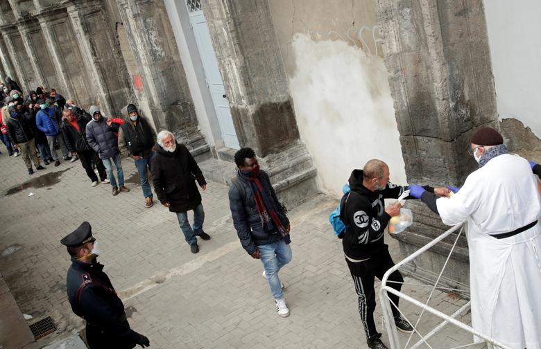 Linh mục Francesco, đeo khẩu trang và găng tay bảo vệ, đưa túi thực phẩm cho những người vô gia cư và người nghèo ở Naples, Italy. Ảnh: Reuters