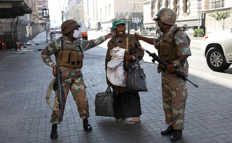 Thành viên lực lượng Quốc gia Nam Phi (SANDF) trò chuyện với một người phụ nữ vô gia cư khi đi tuần ngày đầu tiên trong lệnh phong tỏa toàn quốc. Ảnh: Reuters