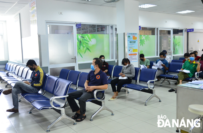 Bệnh nhân đăng ký khám bệnh tại Bệnh viện Đà Nẵng được hướng dẫn ngồi theo khoảng cách đã quy định. 										Ảnh: XUÂN SƠN