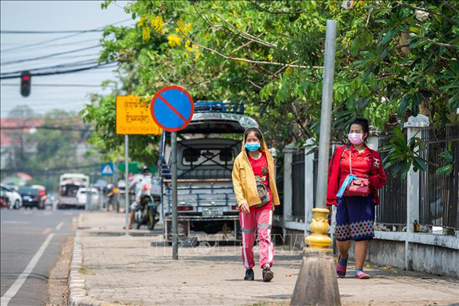 Người dân đeo khẩu trang nhằm ngăn chặn sự lây lan của dịch Covid-19 tại Viêng Chăn, Lào ngày 23-3. Ảnh: THX/TTXVN
