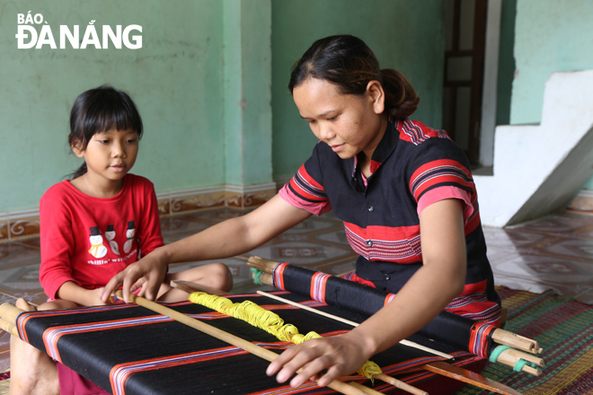 Chị Nguyễn Thị Lang (thôn Tà Lang) bày cho con những thao tác cơ bản của nghề dệt thổ cẩm Cơ tu. Ảnh: V.T.L