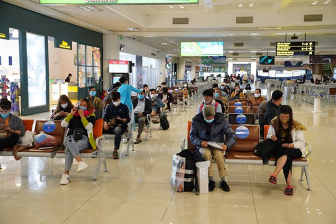 Hành khách tuân thủ giữ khoảng cách khi ngồi tại nhà ga tại sân bay Nội Bài. (Ảnh: Phan Công/Vietnam+)