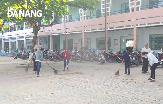 Giáo viên, nhân viên Trường tiểu học Nguyễn Văn Trỗi dọn dẹp vệ sinh sân trường. Ảnh: N.P