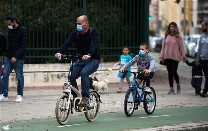 Người dân đeo khẩu trang đạp xe tại Seville, Tây Ban Nha, ngày 26-4-2020. Ảnh: AFP-TTXVN