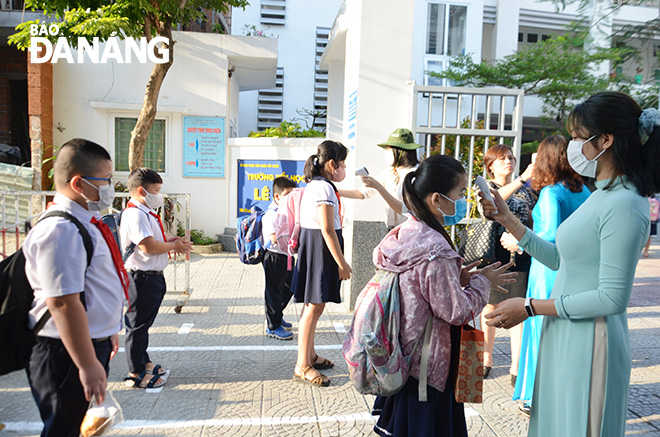 Trường tiểu học Lê Lai (quận Hải Châu) kẻ vạch để học sinh đứng xếp hàng đúng khoảng cách 1m đo thân nhiệt, sát khuẩn trước khi vào lớp. Ảnh: N.P