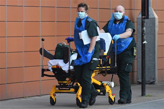  Nhân viên y tế chuyển bệnh nhân Covid-19 tới bệnh viện ở London, Anh ngày 21-4-2020. Ảnh: AFP- TTXVN