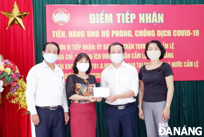 Bà Phạm Thị Nhàn, Chủ tịch Ủy ban MTTQ Việt Nam quận Cẩm Lệ (thứ 2, từ trái sang) tiếp nhận nguồn hỗ trợ từ các doanh nghiệp. 										              Ảnh: ĐỨC NGÔ