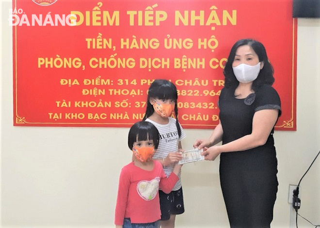 Phó Chủ tịch Ủy ban MTTQ Việt Nam quận Hải Châu Trần Thị Cúc Hương (bìa phải) tiếp nhận số tiền ủng hộ từ hai bé Hồ Xuân Thùy và Hồ Nguyễn Bảo Châu. Ảnh: LAM PHƯƠNG