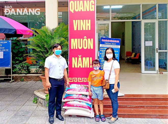 Chủ tịch UBND phường Nại Hiên Đông Cao Đình Hải (bìa trái) tiếp nhận 100kg gạo do cháu Huỳnh Nguyễn Minh Khang ủng hộ.  Ảnh: T.N