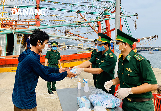Cán bộ chiến sĩ Trạm kiểm soát Biên phòng Mân Quang phát khẩu trang và tuyên truyền các biện pháp phòng, chống dịch cho ngư dân. Ảnh XUÂN DŨNG