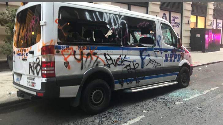 Xe cảnh sát New York bị người hâm mộ sơn bậy trong cuộc đụng độ với người biểu tình. Ảnh: CNN