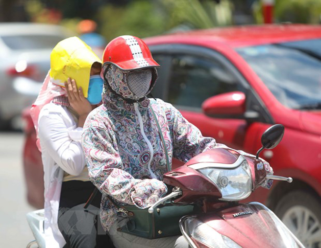  Thời điểm giữa trưa, nếu phải di chuyển trên đường, người dân cần trang bị đồ chống nắng để đảm bảo sức khỏe. (Ảnh: Thanh Tùng/TTXVN)