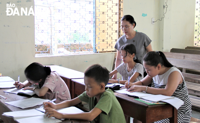 Bà Phạm Thị Hoài Mỹ (đứng) chỉ dạy tận tình cho các em học sinh của lớp học thiện nguyện. Ảnh: LAM PHƯƠNG	
