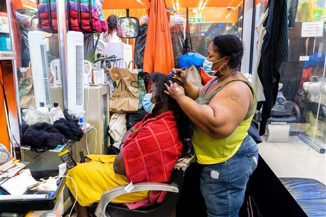 Người dân đeo khẩu trang tại một cửa hàng làm tóc ở Peckham, London, Anh, ngày 13-7. Ảnh: AFP/TTXVN