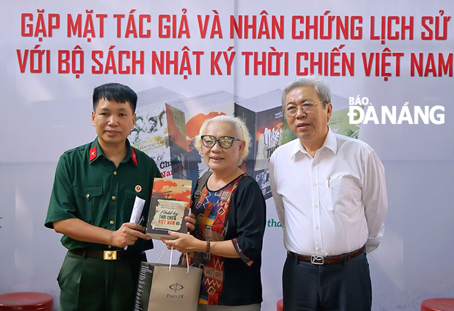Nhà văn Đặng Vương Hưng (trái) tặng sách cho thân nhân gia đình Anh hùng LLVTND - liệt sĩ, nhà văn Chu Cẩm Phong tại Thành phố Hồ Chí Minh, tháng 7-2020. Ảnh: P.V