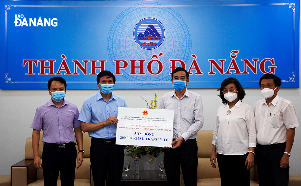 Phó Chủ tịch UBND thành phố Lê Trung Chinh (thứ 3, bên phải) tiếp nhận 5 tỷ đồng và 200.000 khẩu trang từ thành phố Hải Phòng. Ảnh: XUÂN DŨNG
