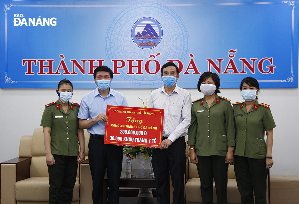 Phó Chủ tịch UBND thành phố Lê Trung Chinh (thứ 3, bên phải) thay mặt Công an thành phố tiếp nhận 200 triệu đồng và 30.000 khẩu trang từ Công an thành phố Hải Phòng. Ảnh: XUÂN DŨNG