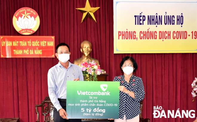 Chủ tịch Ủy ban MTTQ Việt Nam thành phố Đặng Thị Kim Liên (phải) tiếp nhận hỗ trợ từ đại diện Ngân hàng TMCP Ngoại thương Việt Nam Vietcombank. Ảnh: L.P