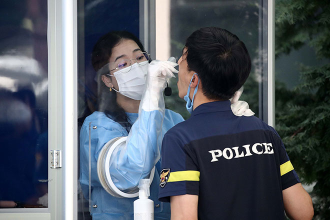 Nhân viên y tế lấy mẫu xét nghiệm Covid-19 đối với một nhân viên cảnh sát ở Seoul. Ảnh: AFP/Getty Images