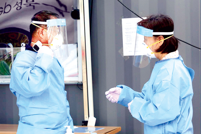 Một nhân viên y tế đang đo thân nhiệt của chính anh trong khi làm xét nghiệm Covid-19 tại một bệnh viện dã chiến ở Seoul (Hàn Quốc) ngày 26-8. Ảnh: AP