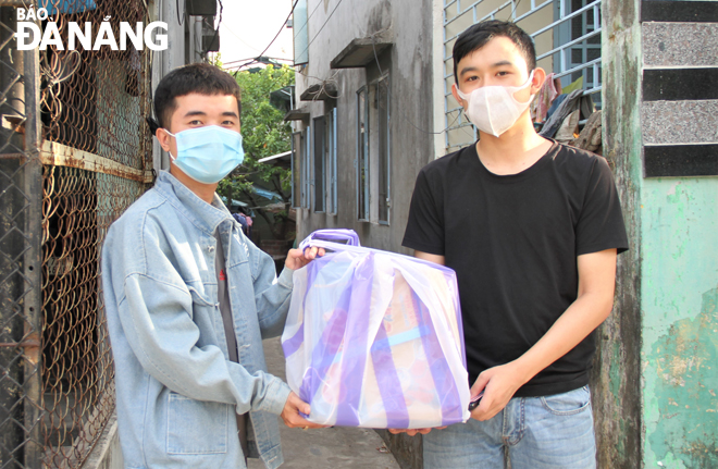Đặng Tấn Tín (trái) trao quà hỗ trợ sinh viên ngoại tỉnh mắc kẹt lại thành phố trong mùa dịch.  Ảnh: L.P