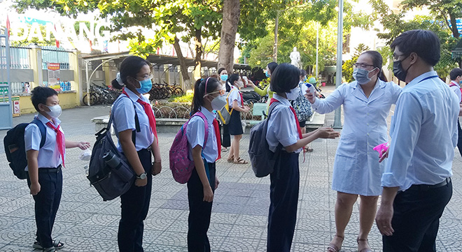Nhân viên y tế Trường THCS Nguyễn Huệ (quận Hải Châu) đo thân nhiệt cho học sinh ngay sau khi các em bước vào cổng trường.