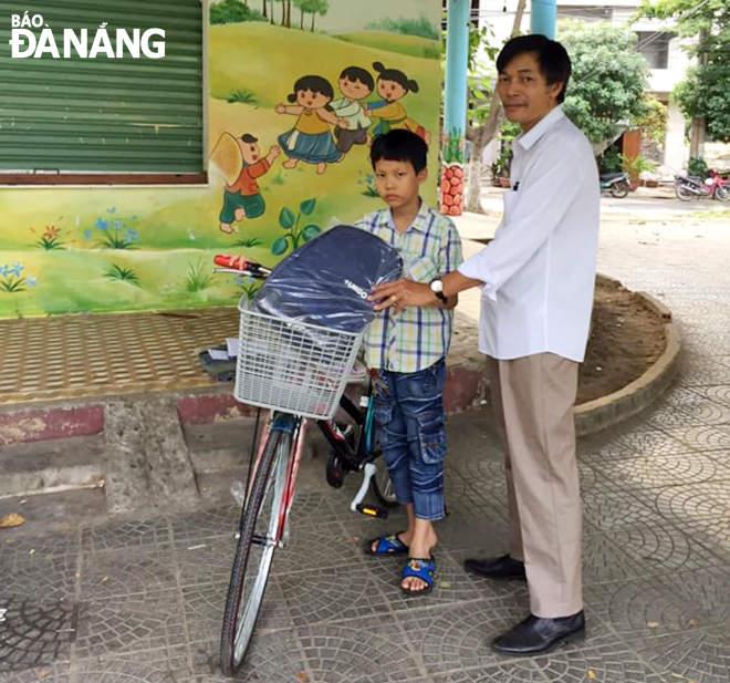 Ông Lê Văn Hùng, đại diện Chi hội Khuyến học Tân Phú, tặng phương tiện đến trường cho học sinh nghèo trong khu vực. (Ảnh chụp tháng 7-2020)     Ảnh: HUỲNH LÊ