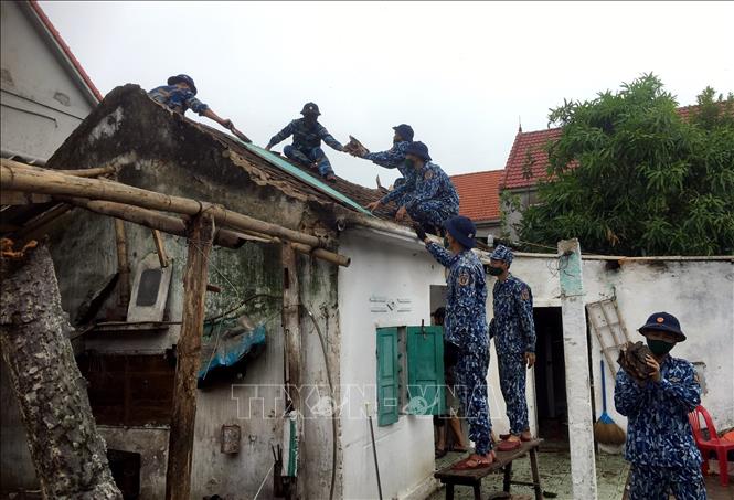 Cán bộ, chiến sĩ Hải đội 102 giúp nhân dân xã Cương Gián lợp lại mái nhà do bão làm hư hại. Ảnh: TTXVN