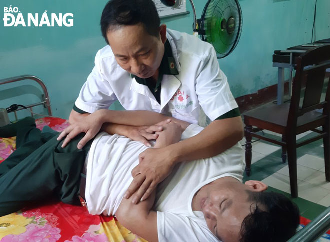 Thiếu tá Ninh Công Khánh chữa trị cho người dân bằng phương pháp đông- tây y kết hợp. Ảnh: HOÀNG SA