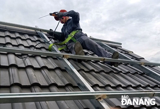 Công nhân ngành Điện đang thi công công trình điện mặt trời mái nhà tại tuyến đường Thăng Long, quận Cẩm Lệ. Ảnh: HUỲNH LÊ