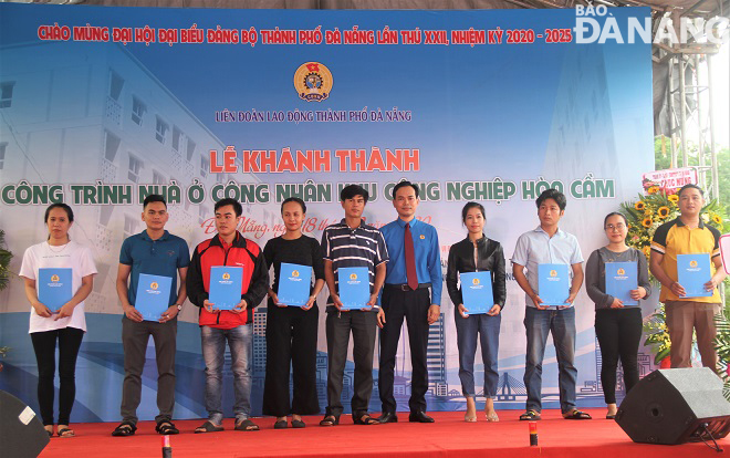 Chairman of the municipal Labour Union Nguyen Duy Minh (5th right, in blue) handing housing rental decisions to 18 workers in the Hoa Cam Industrial Park