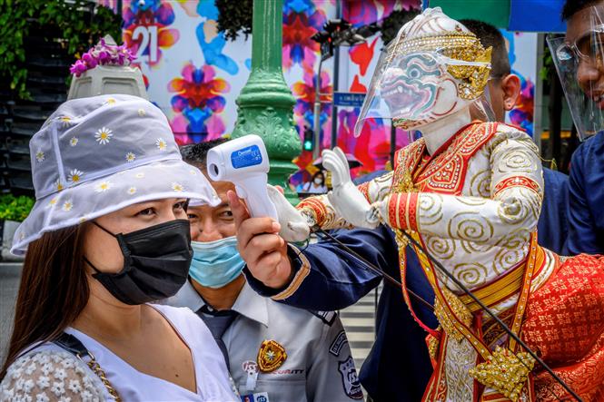 Đo thân nhiệt cho khách thăm quan phòng lây nhiễm COVID-19 tại một ngôi đền ở Bangkok, Thái Lan. Ảnh: AFP/TTXVN