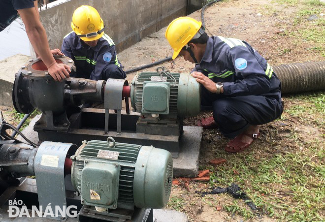 Công nhân Công ty Thoát nước và Xử lý nước thải Đà Nẵng lắp đặt máy bơm để chuẩn bị vận hành hạ thấp mực nước hồ Công viên 29 Tháng 3 nhằm chống ngập úng cho khu vực trung tâm thành phố. Ảnh: HOÀNG HIỆP